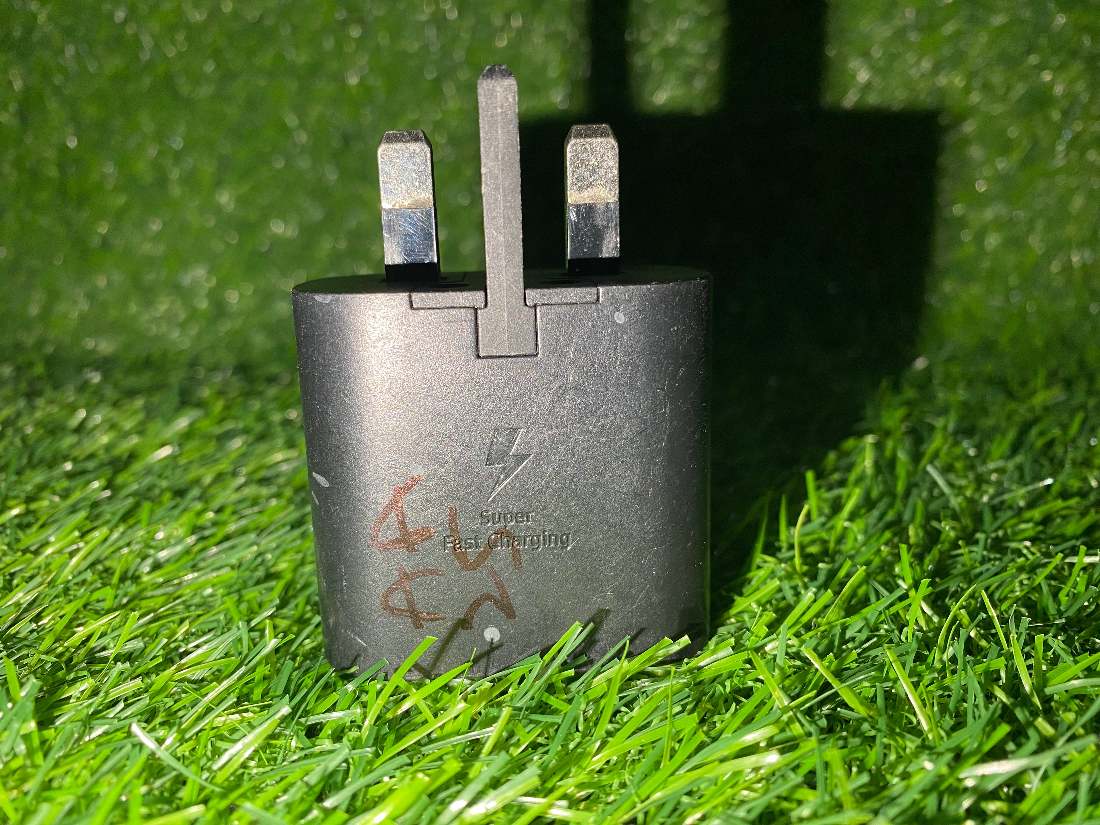 Black charging adapter on green grass