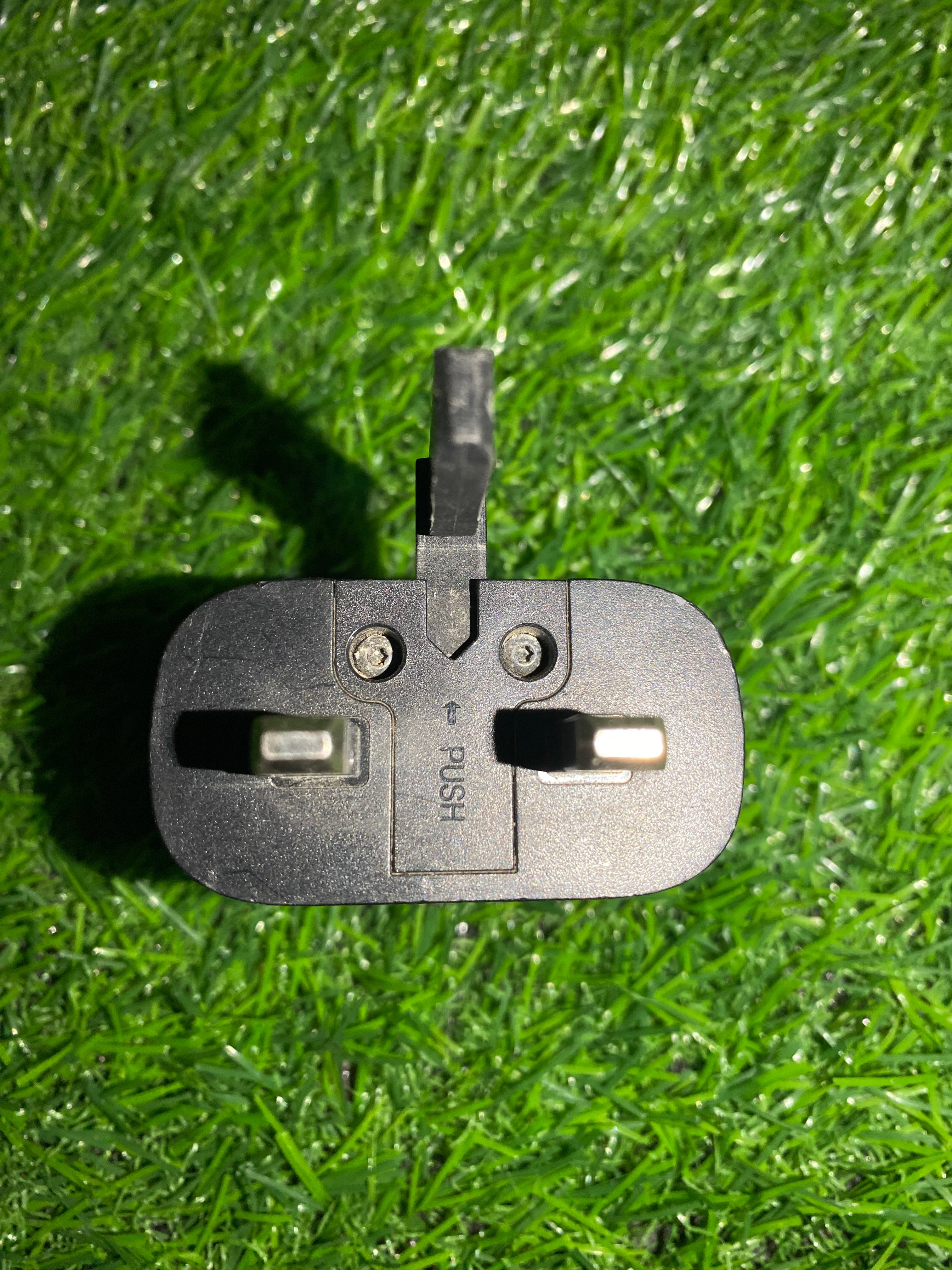 Black electrical plug on a grassy background