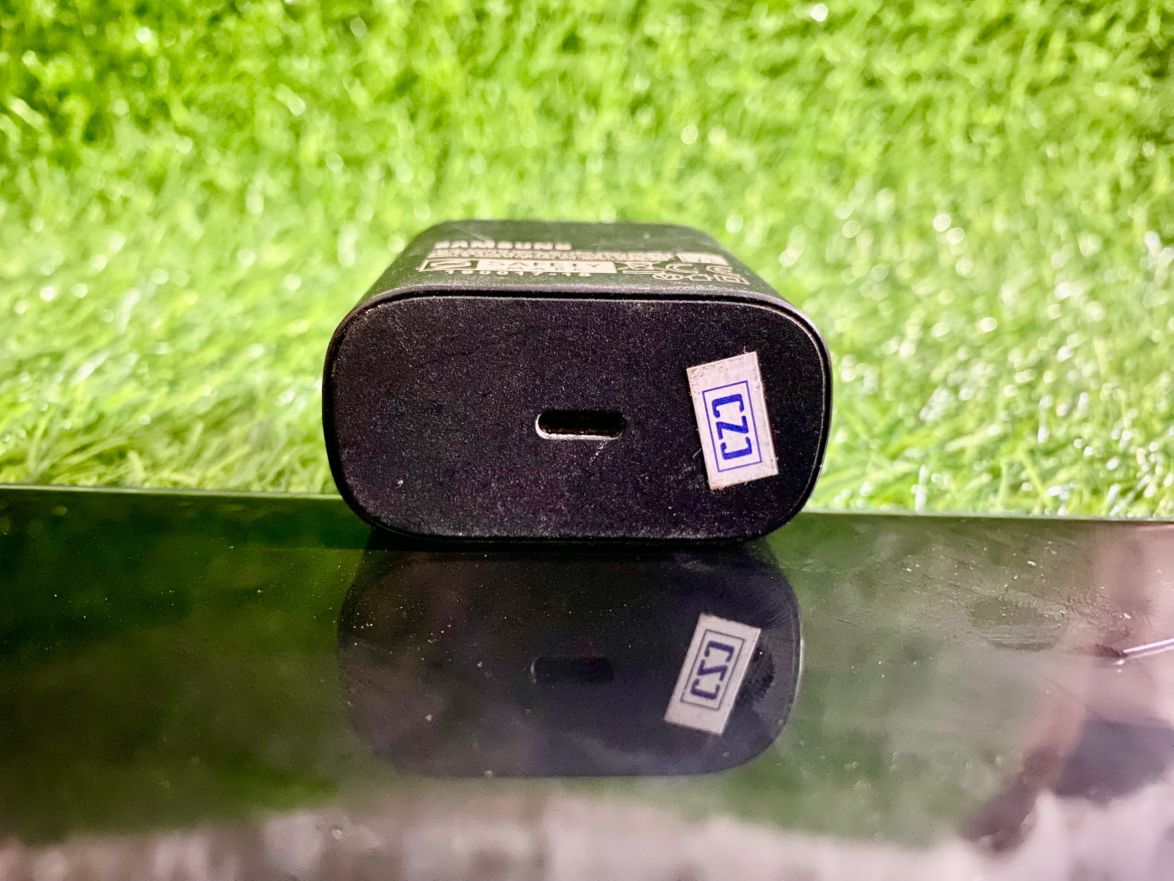 Black electronic device with a label on a reflective surface and grass background